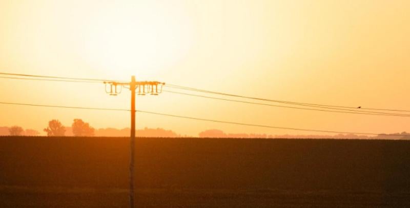 Three-phase line silhouetted by setting sun